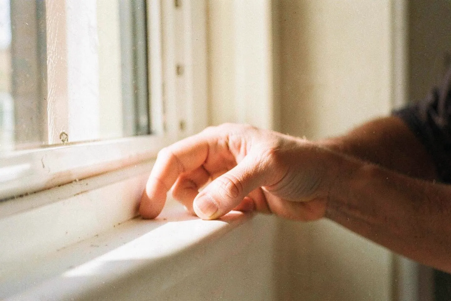 A hand resting on a sunlit windowsill