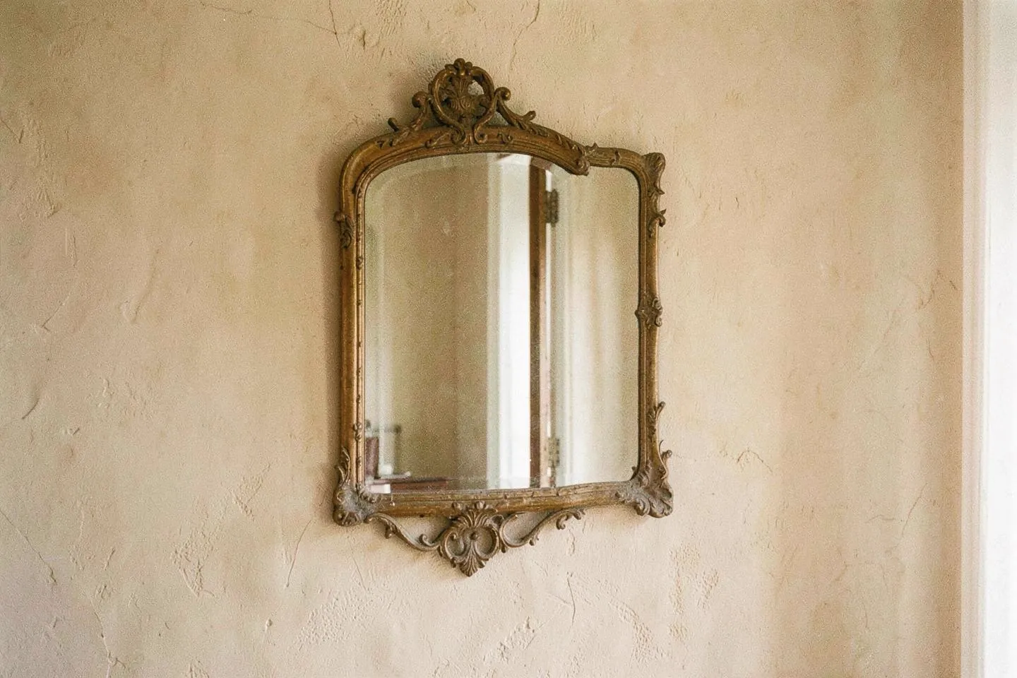 An antique mirror on a warm plaster wall